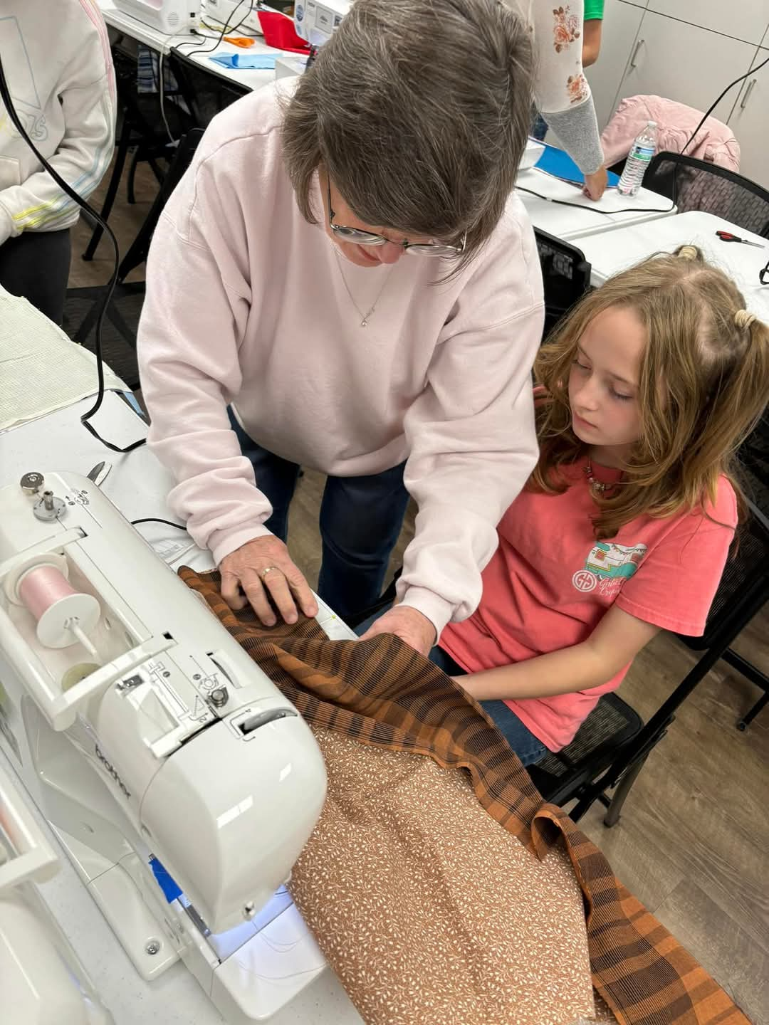 adult teaching child to sew