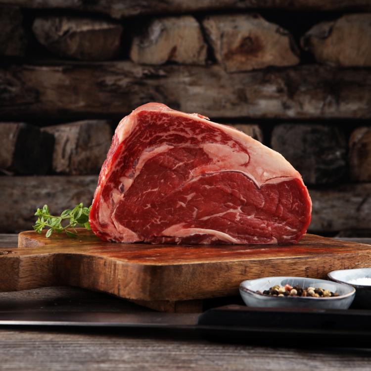  Raw fresh meat Ribeye Steak, seasoning and meat fork on dark background