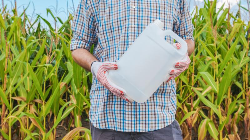 Farmer holding unlabeled pesticide jug in field